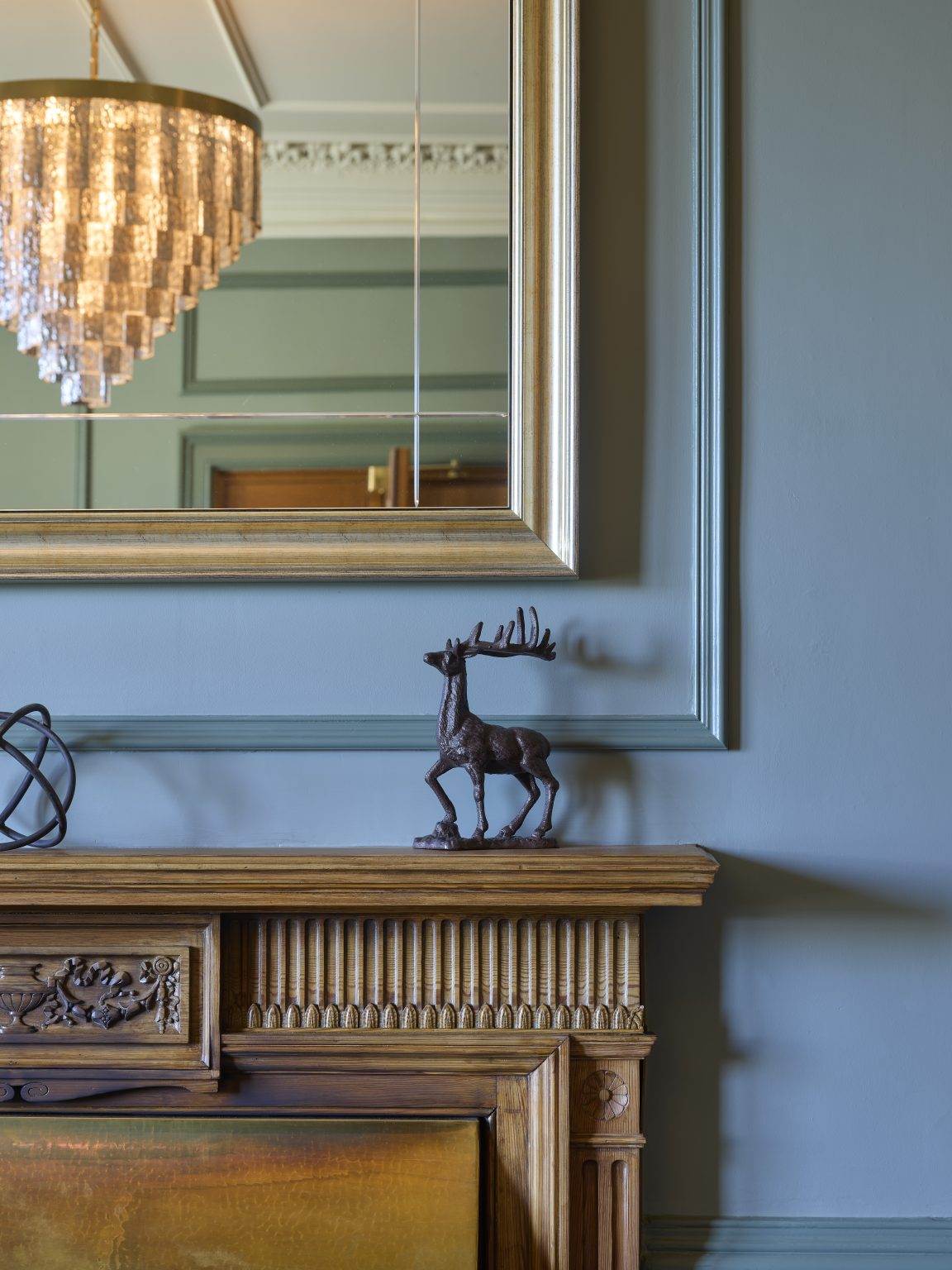 Decorative mantelpiece with a bronze deer sculpture and mirror, showcasing elegant details in a hospitality fit-out design.