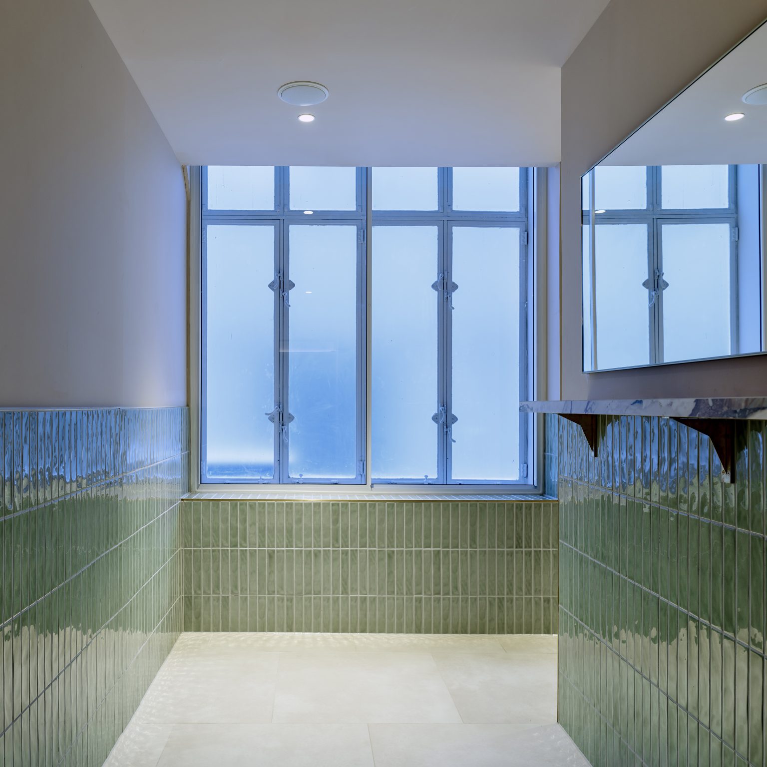 Green-tiled washroom area showcasing contemporary design elements in hospitality fit-outs.