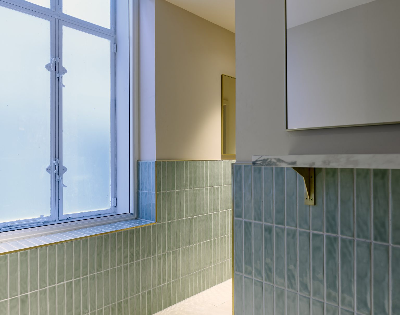 Bathroom area with green tiling and frosted windows, part of a hospitality fit-out project focused on modern aesthetics.