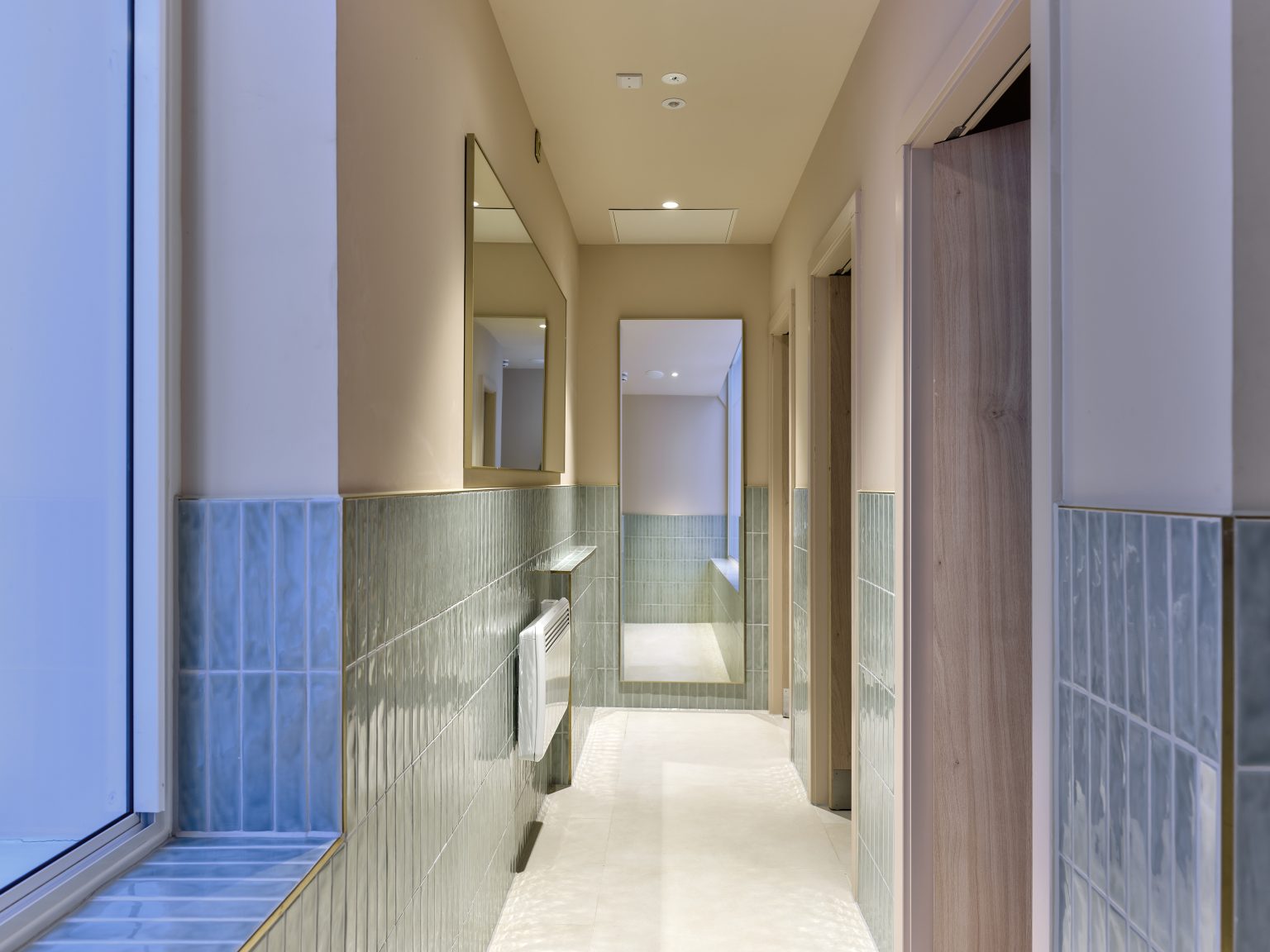 Elegant hotel hallway with teal tiling and large mirrors, offering a glimpse of the upscale hospitality fit-out.