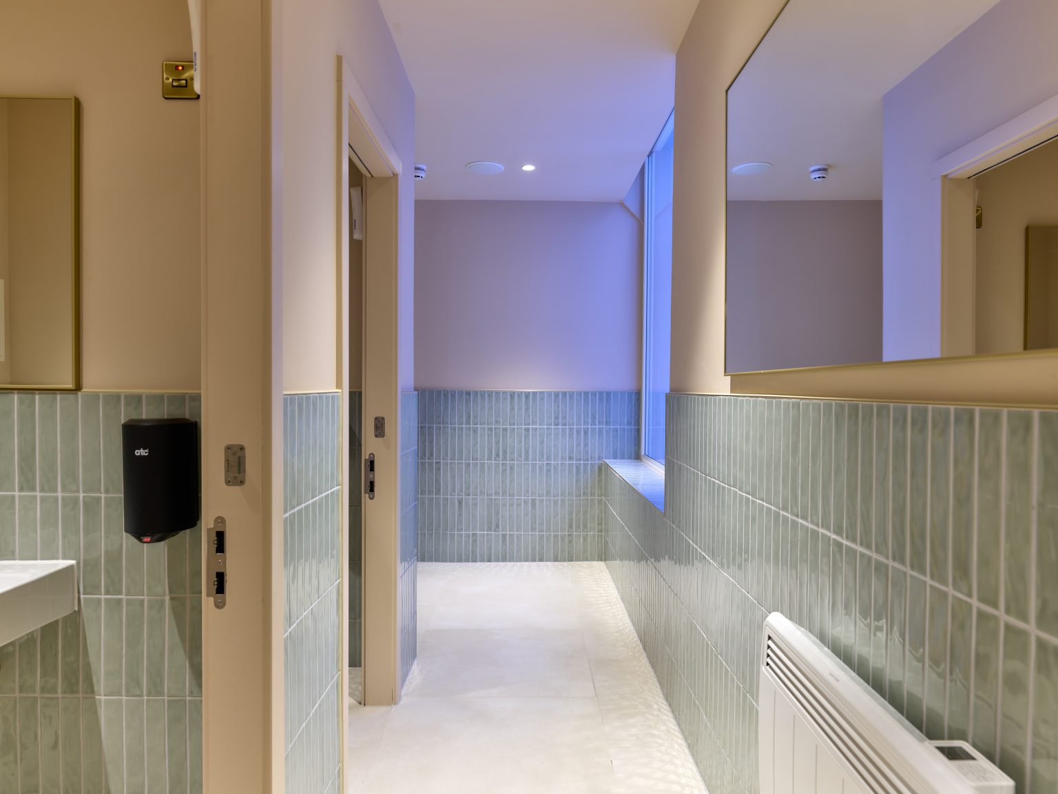 Guest washroom entrance with tasteful teal tiles and modern fittings, illustrating attention to detail in hospitality design.