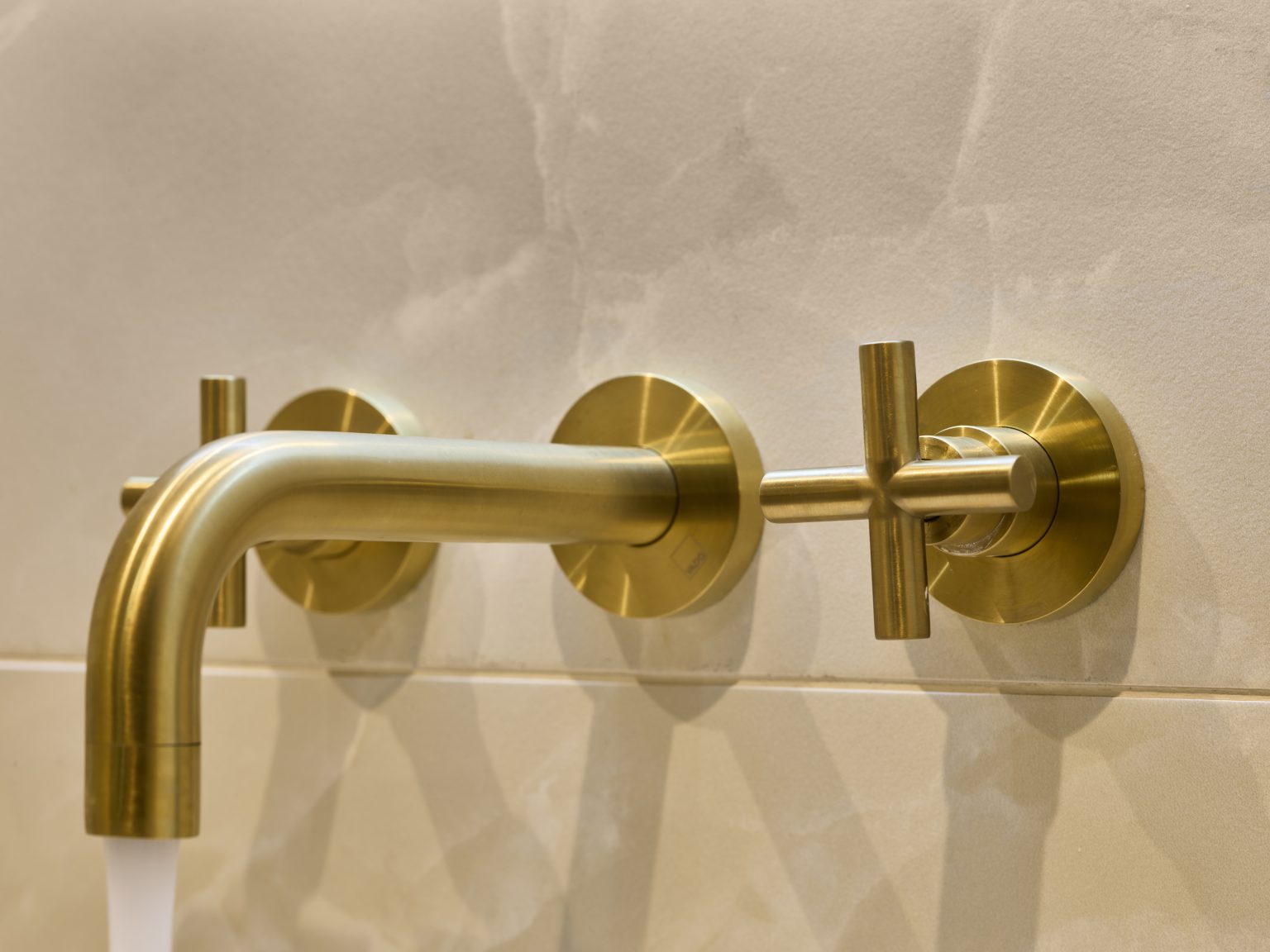 Close-up of brass door handle with textured grip in a luxury hotel bathroom, showcasing attention to detail in the hospitality fit-out.