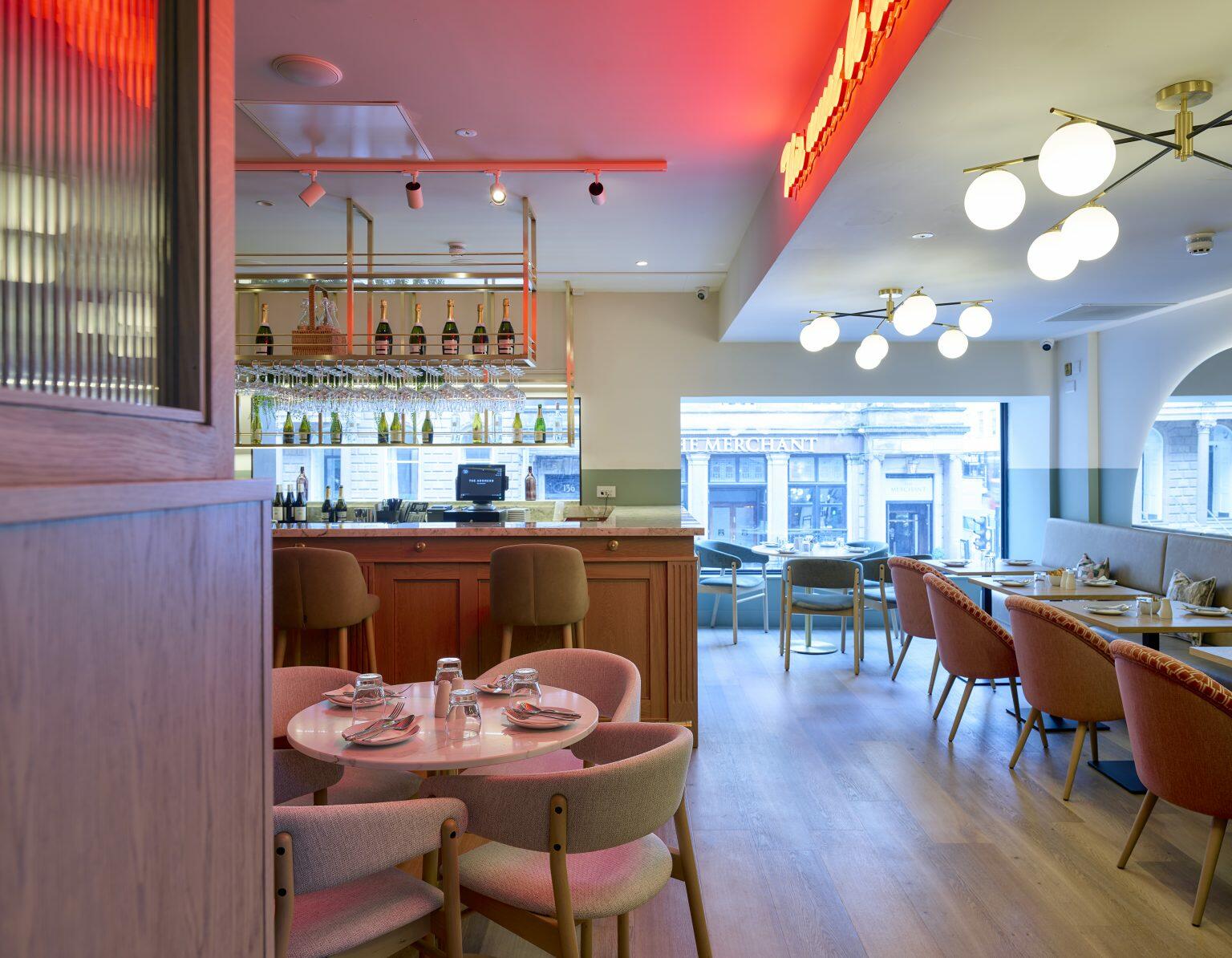 Trendy hospitality dining area with neon sign reading 'This must be the place', featuring stylish seating, marble bar top, and modern decor elements.