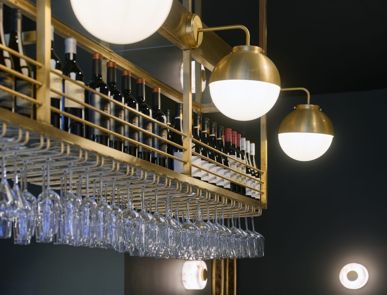 Stylish wine rack and glass storage with brass accents in a hospitality bar fit-out.